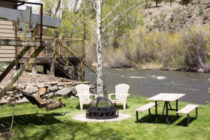 fire pit and two adirondak chairs sitting by the river