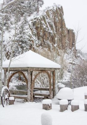 snow covered cliffs  and brown wooden arbor on the banks of the river