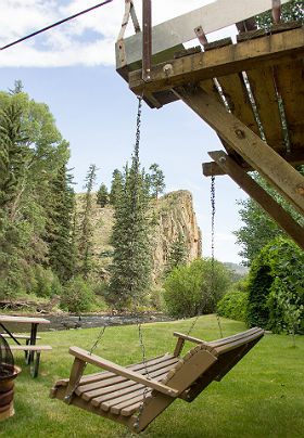 Hanging porch swing overlooking summer time view of private cliffs and river