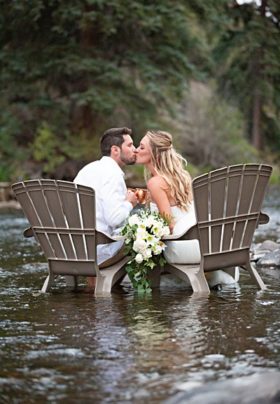 mountain bride and groom kissing in the river and toasting with copper cups