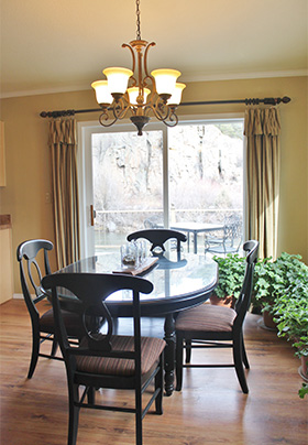 A dark brown diningroom table with four chairs sits in the center of a brightly lit room