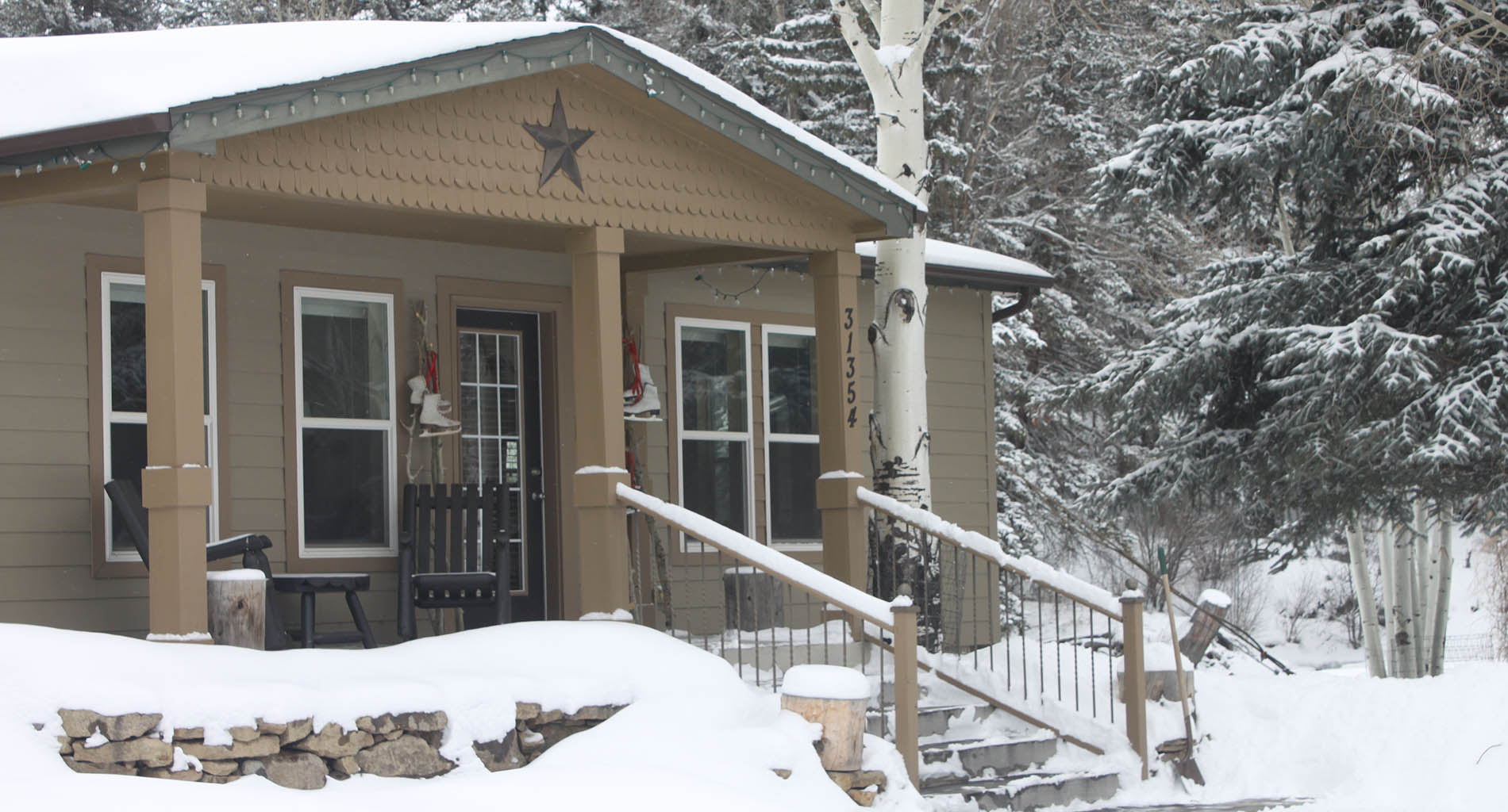 A view of a tan house with railed walkway covered with a blanket of white snow