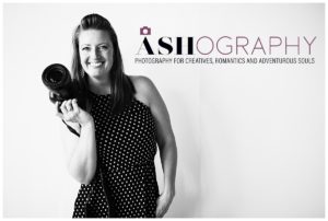 black and white photo of photographer Ashlee Bratton holding a camera in front of a white background