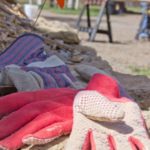 A pair of pink gloves laying on the ground with a view of a construction site in background