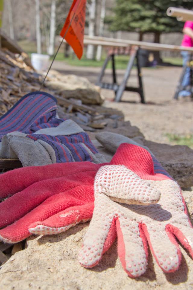 A pair of pink gloves laying on the ground with a view of a construction site in background